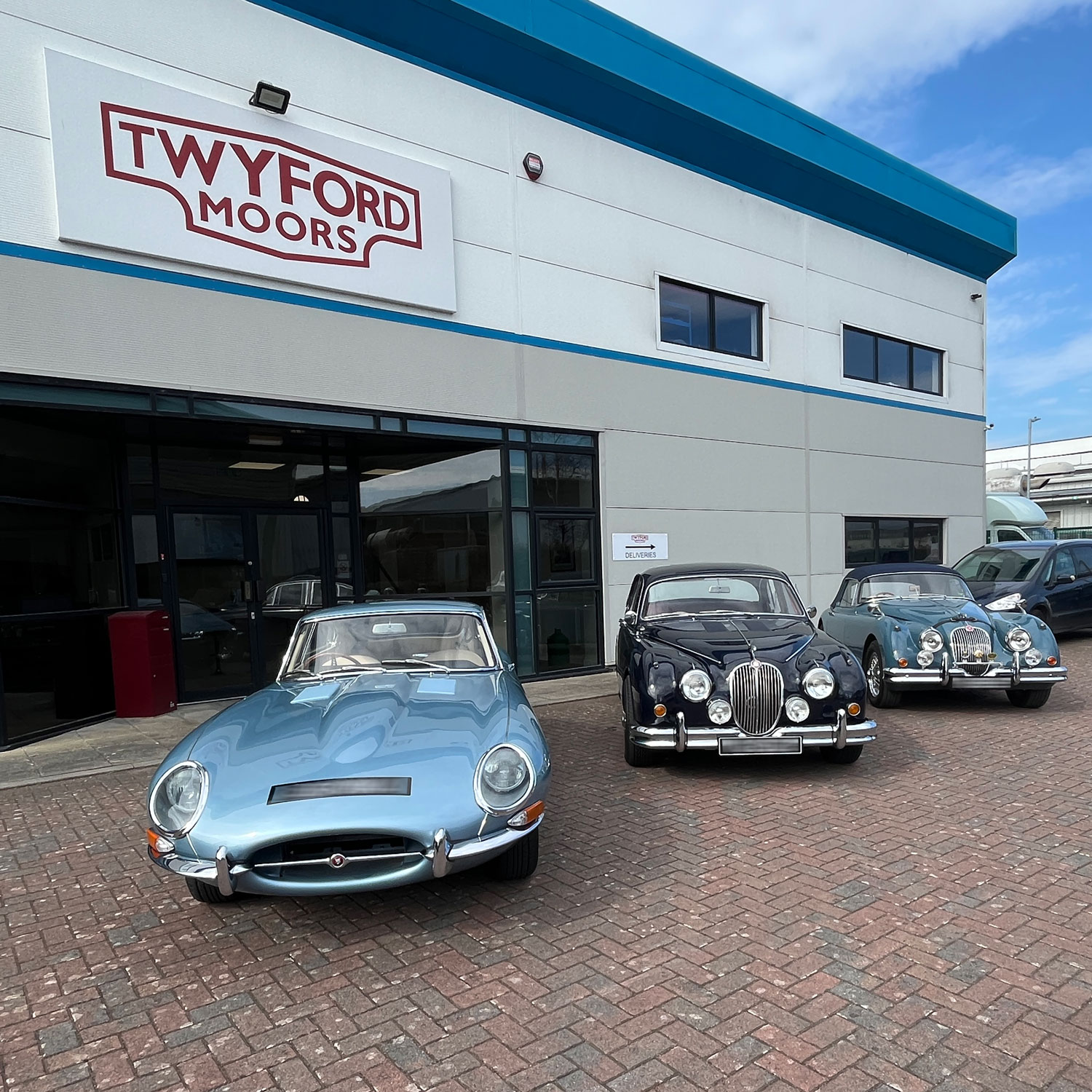 Jaguar XK150, MK2 and E-Type outside classic car workshop